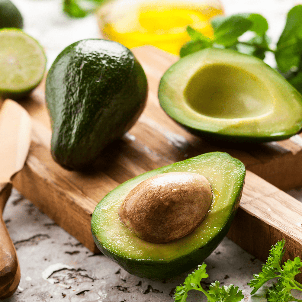 avocados open on wooden chopping board with citrus surrounds