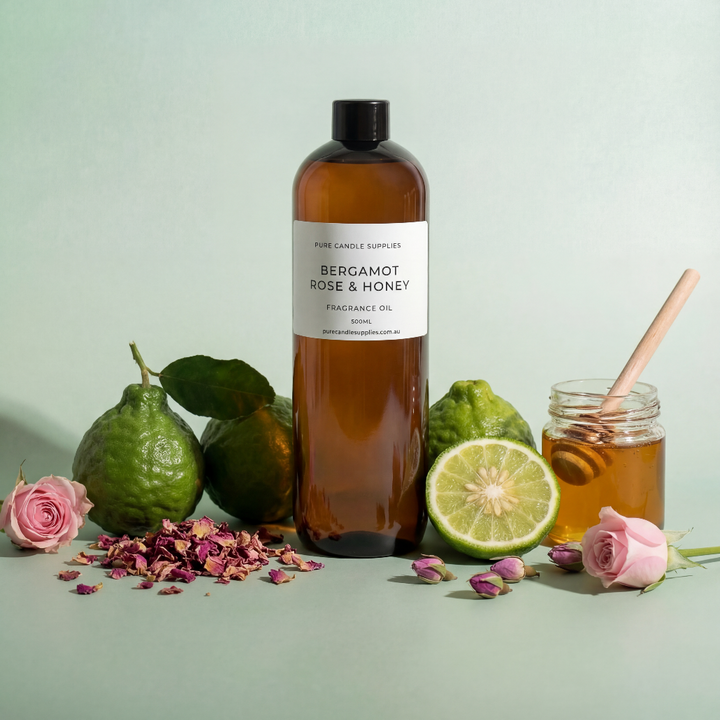 Bottle of Bergamot Rose & Honey fragrance oil with citrus fruits, flowers, and honey on a light green background
