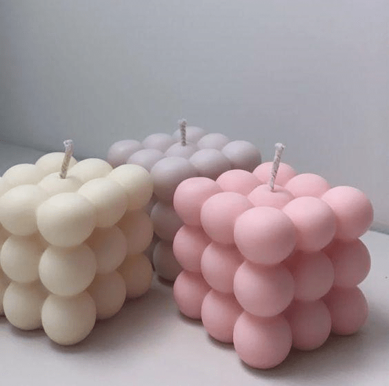 cube bubble mould candles in pink white and mauve on grey background