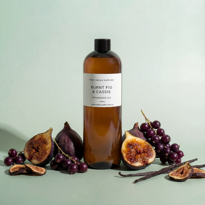 Brown bottle labeled 'Burnt Fig & Cassis' with figs, grapes, and vanilla beans on a light green background