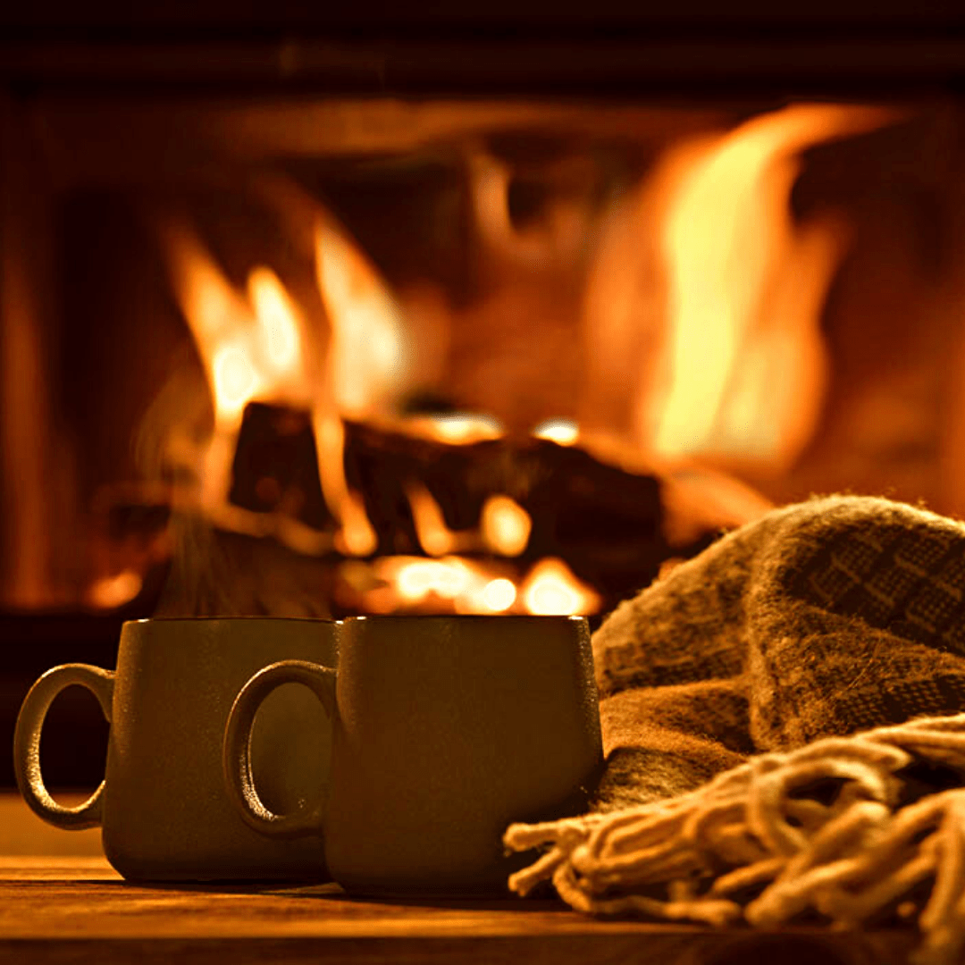 Lit fireplace with two mugs & blanket in the foreground