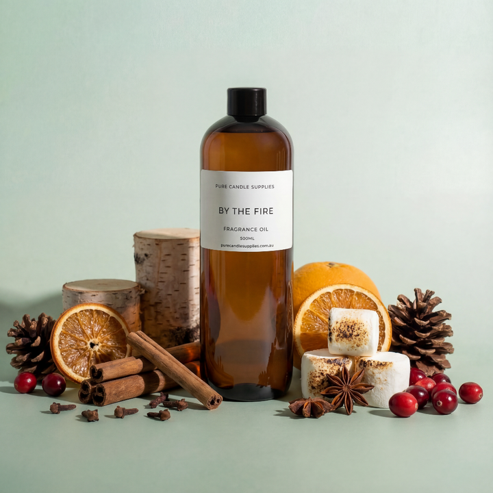 Brown bottle labeled 'By the Fire' surrounded by decorative items on a light green background