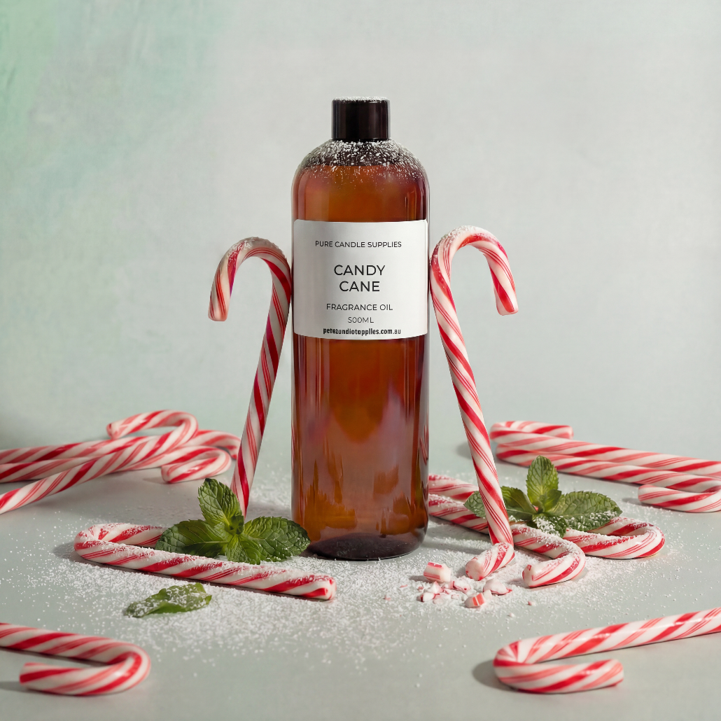 Bottle of candy cane fragrance oil with candy canes and mint leaves on a light background