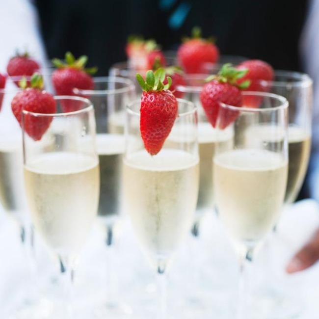 Group of glasses filled with champagne with strawberries on the rim