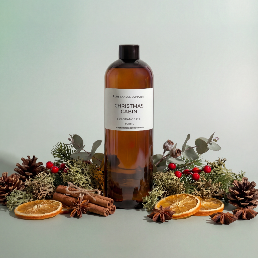 Bottle of 'Christmas Cabin' fragrance oil with decorative elements on a light background