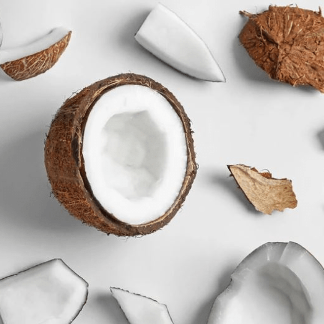 cut open coconut with coconut fragments scattered around on white background