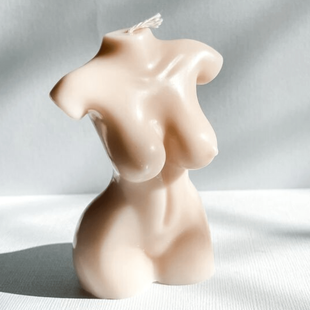 curvy female body candle in beige coloured wax on a textured grey background