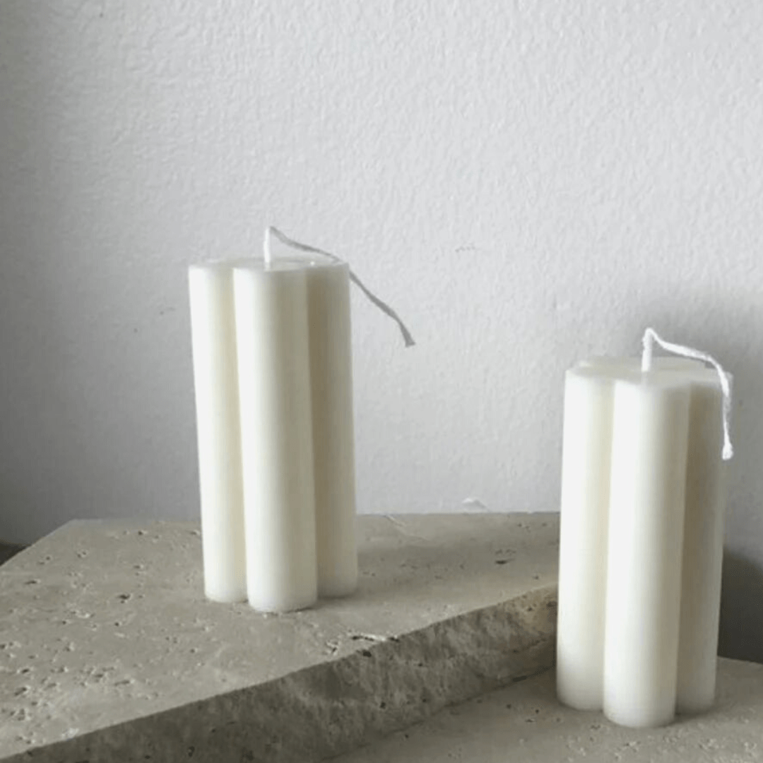 two flower shaped pillar candles on stone steps with white textured background