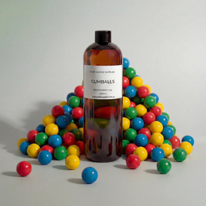 Bottle of 'Gumballs' fragrance oil surrounded by colorful gumballs on a light gray background