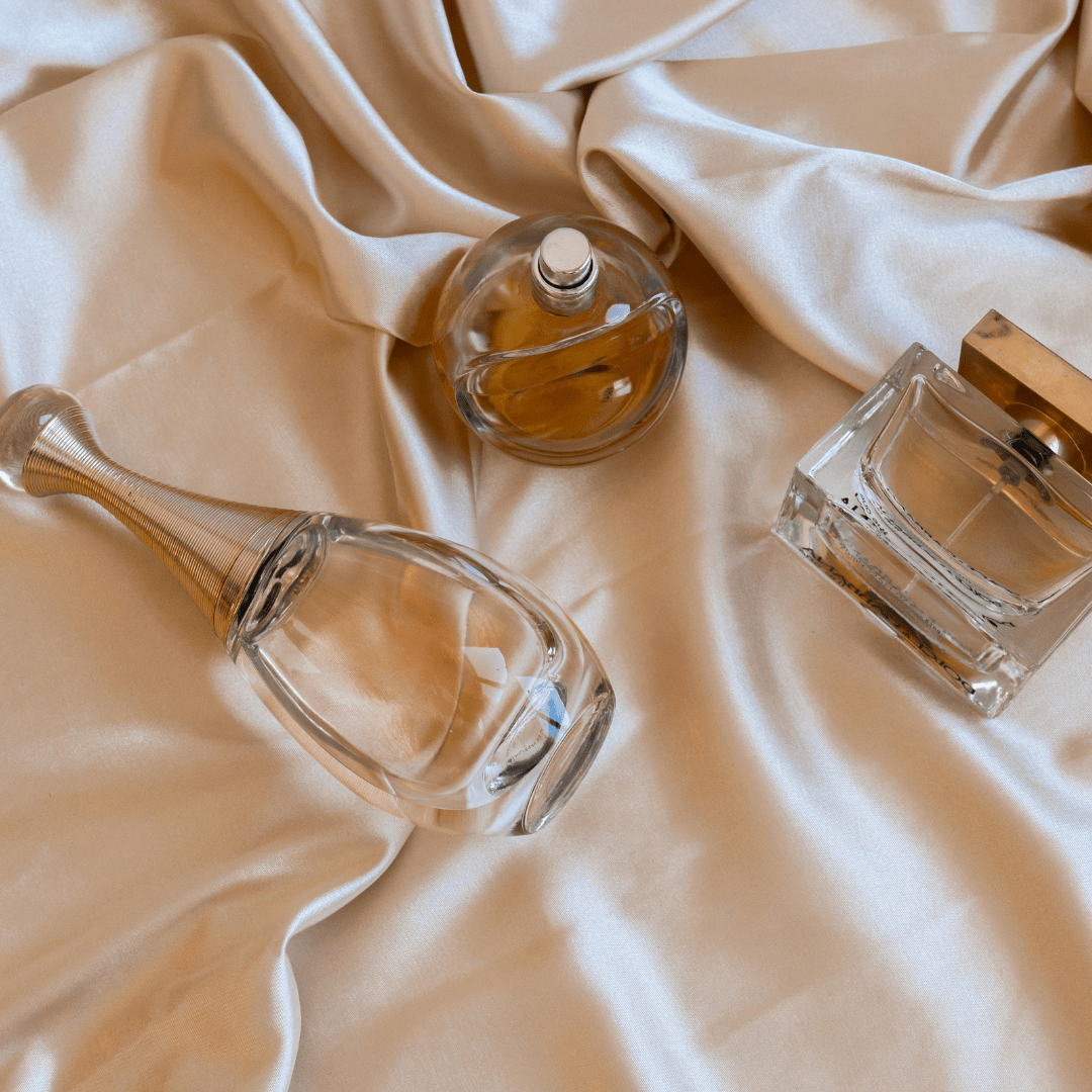 Assorted perfume bottles laying on silky champagne sheets