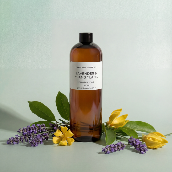 Brown bottle of lavender and ylang ylang fragrance oil with flowers on a light background