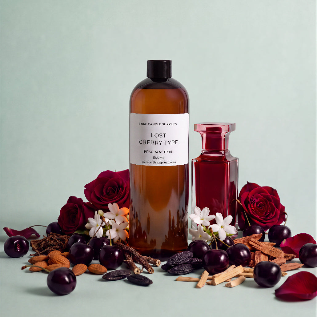 A bottle of Pure Candle Supplies 'Lost Cherry Type' fragrance oil stands next to a small red glass bottle, surrounded by cherry blossoms, cherries, cinnamon sticks, and rose petals on a pale mint background.