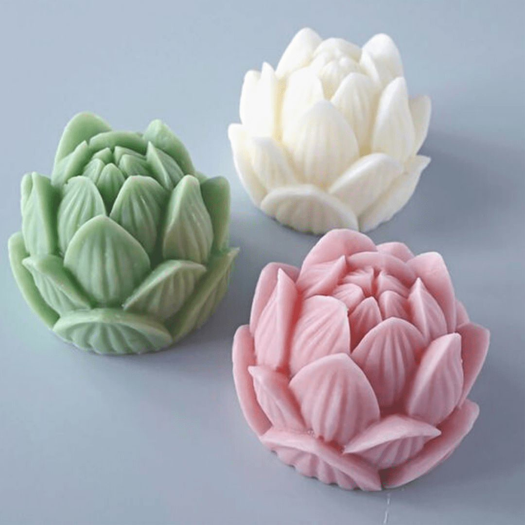 three lotus flower shaped candles in green white and pink on grey background