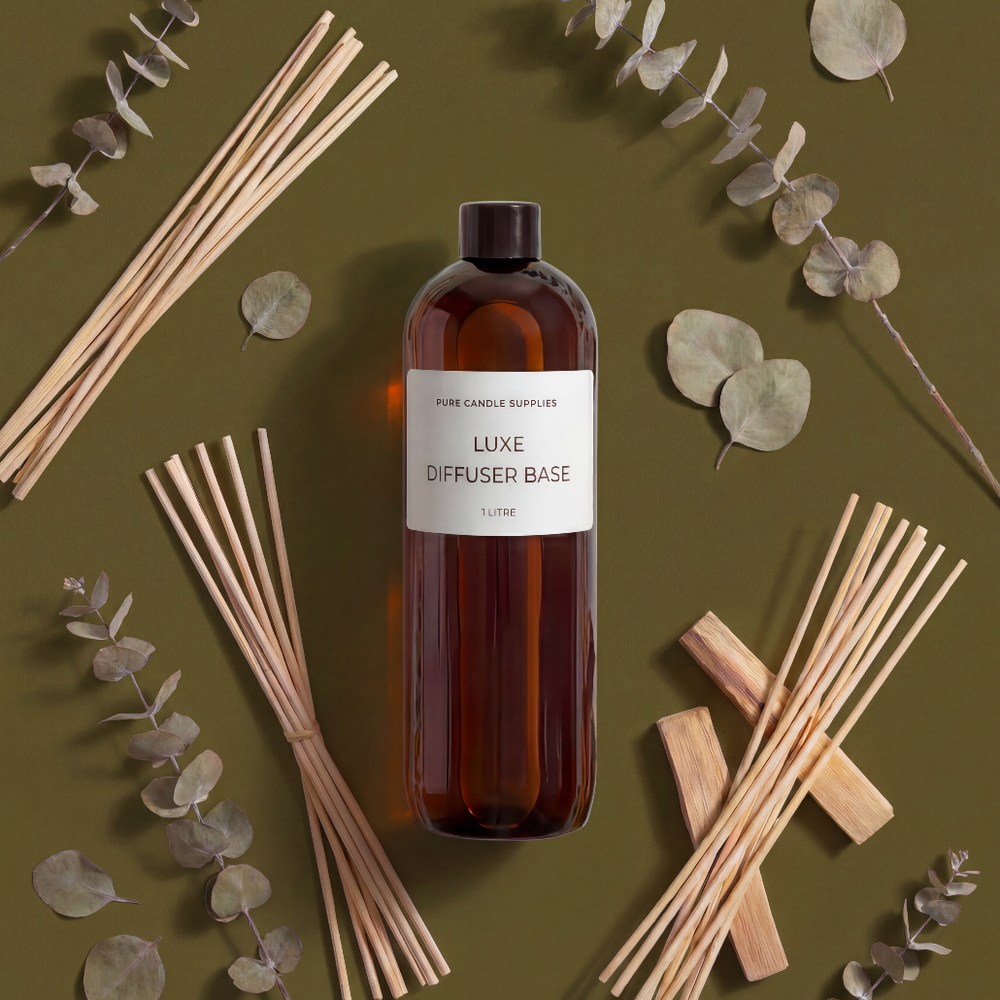 Bottle of Luxe Diffuser Base with reeds and eucalyptus leaves on a green background