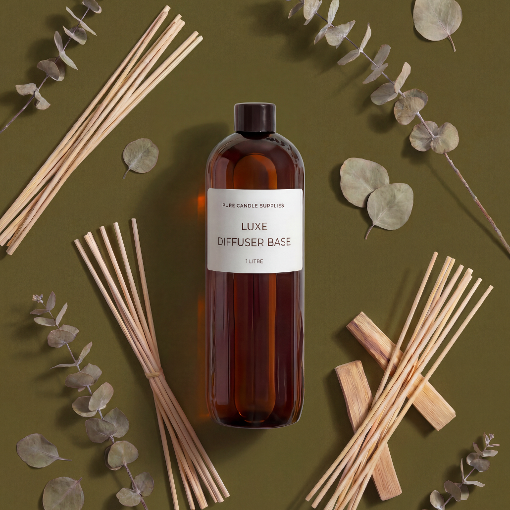 Bottle of Luxe Diffuser Base with reeds and eucalyptus leaves on a green background