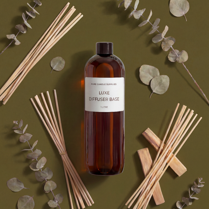 Bottle of Luxe Diffuser Base with reeds and eucalyptus leaves on a green background