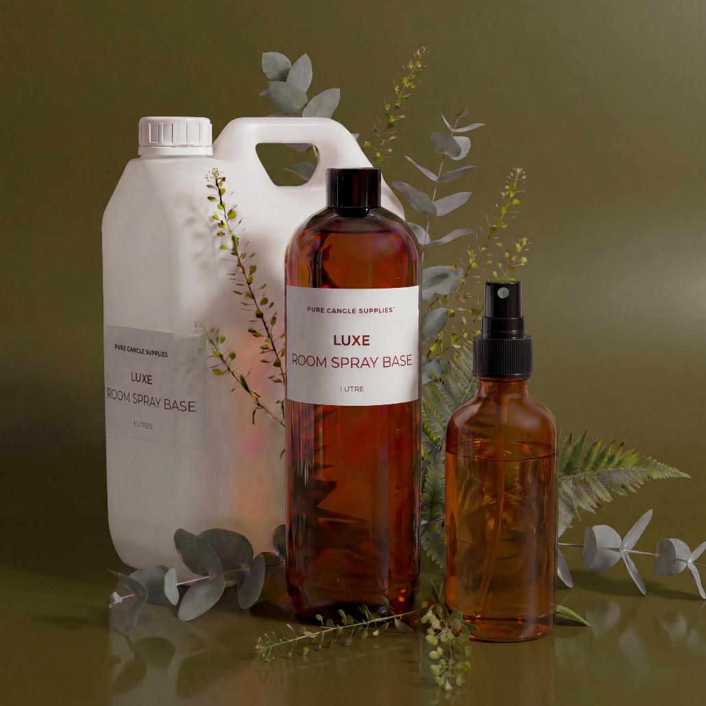Room spray bottles with labels on a reflective surface with greenery.
