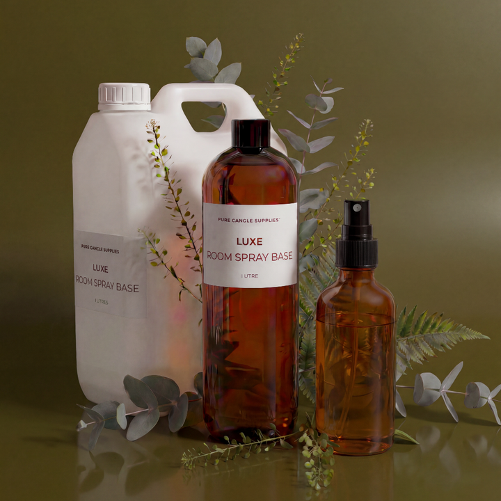 Room spray bottles with labels on a reflective surface with greenery.