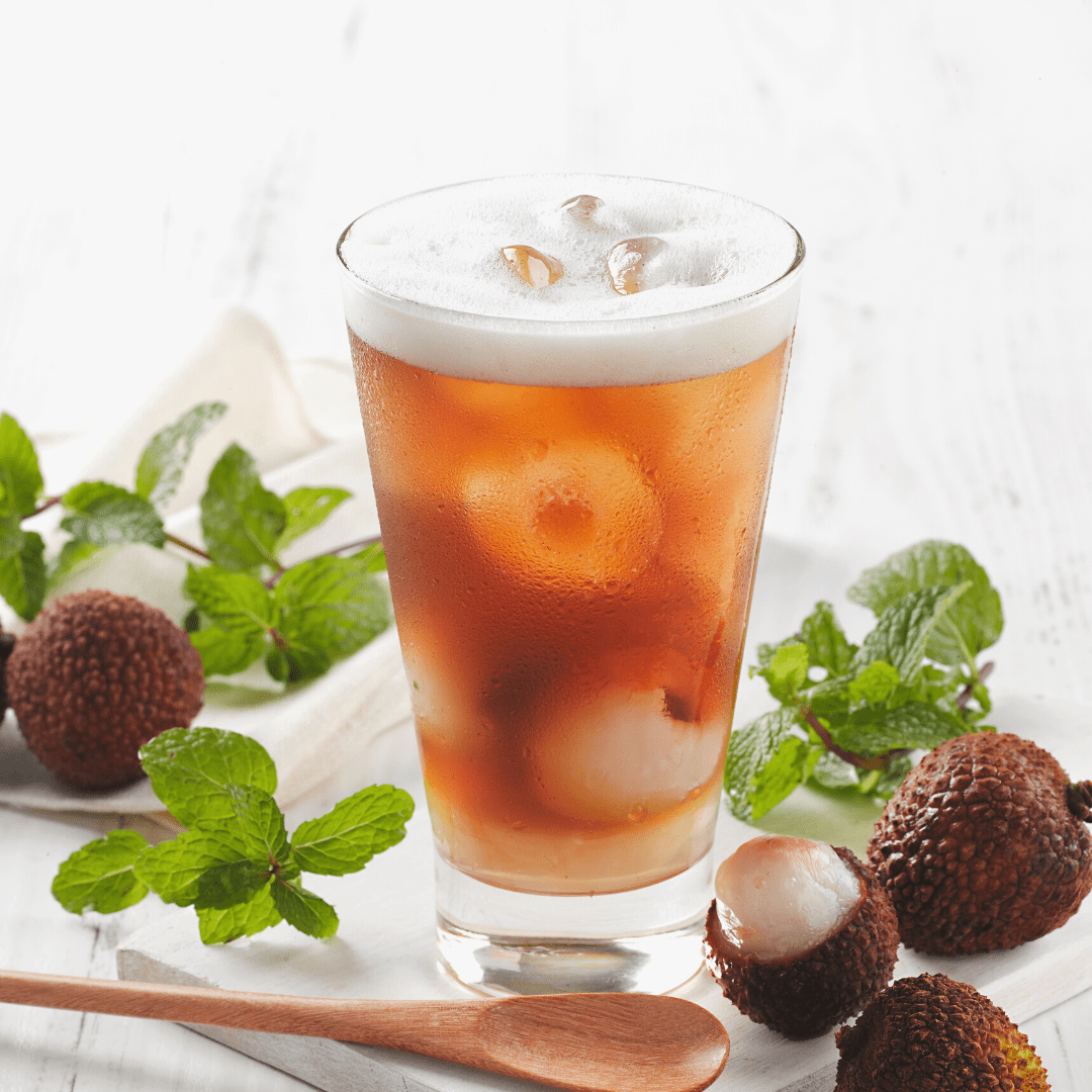 Glass of lychee and black tea with lychee and fresh mint surrounding