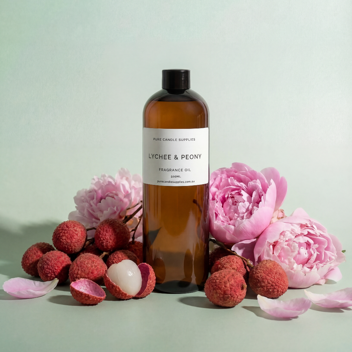 Bottle of Lychee & Peony fragrance oil with lychees and pink flowers on a light background