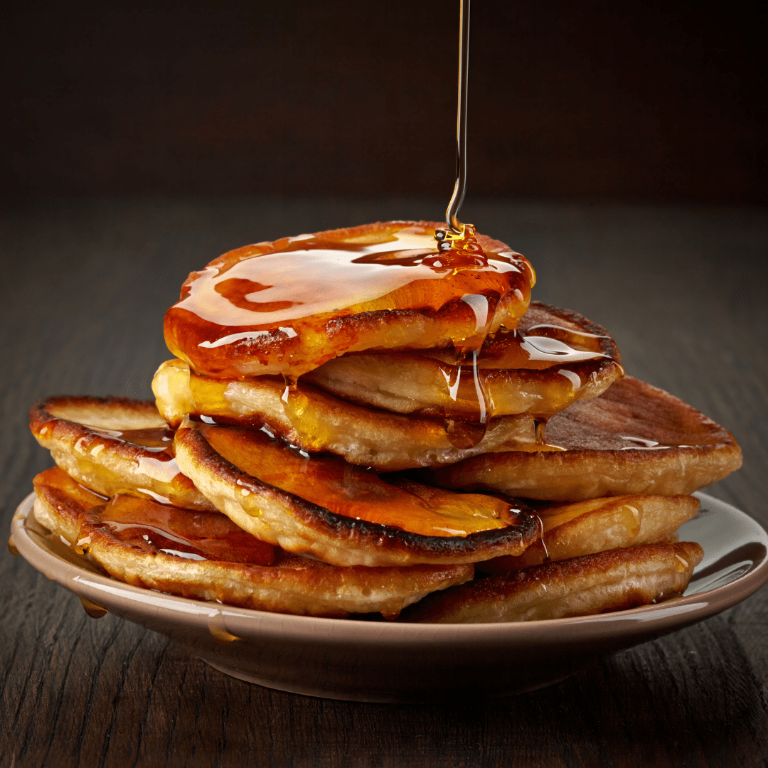 stack of pancakes with layers of maple syrup poured on top