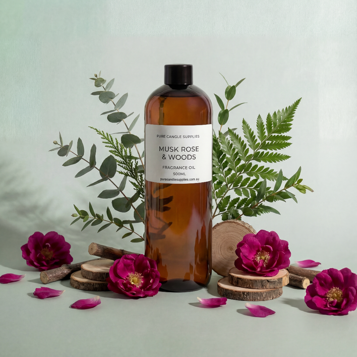 Bottle of Musk Rose & Woods fragrance oil with flowers and leaves on a light background