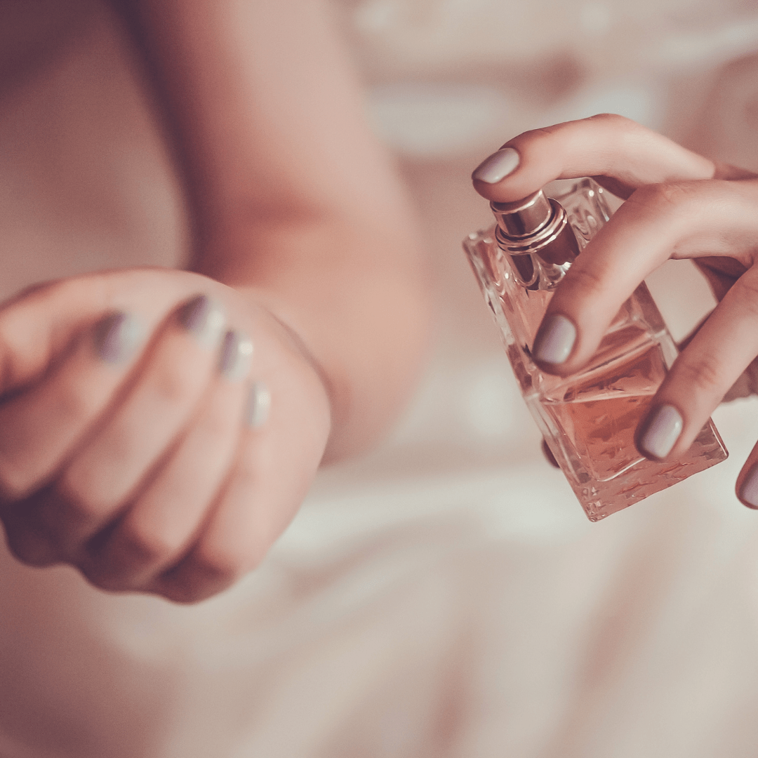 woman spraying perfume on wrists