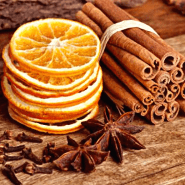 Stack of orange slices next to quills of cinnamon & star anise