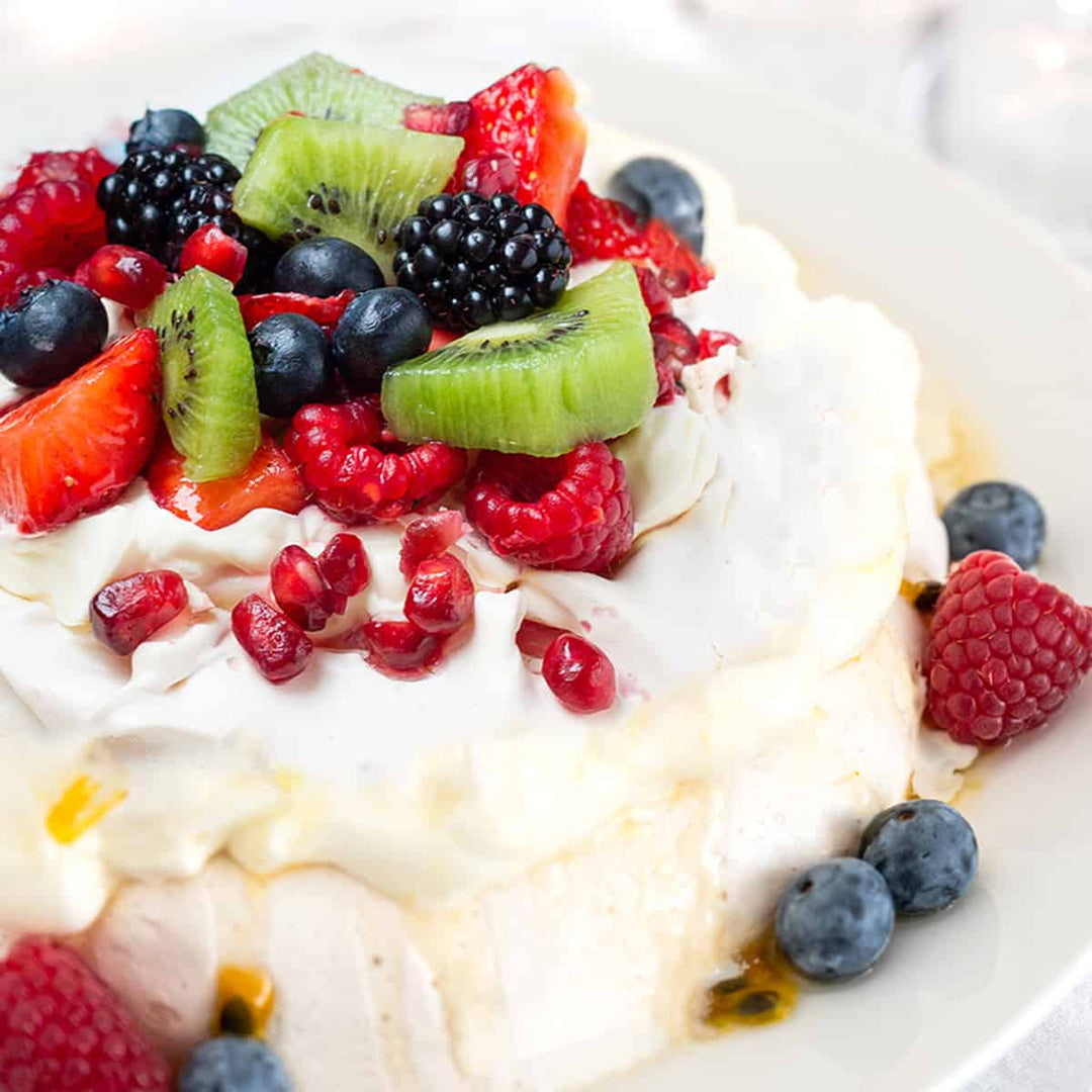 meringue base with fresh whipped cream, topped with berries, kiwi fruit and passionfruit pulp