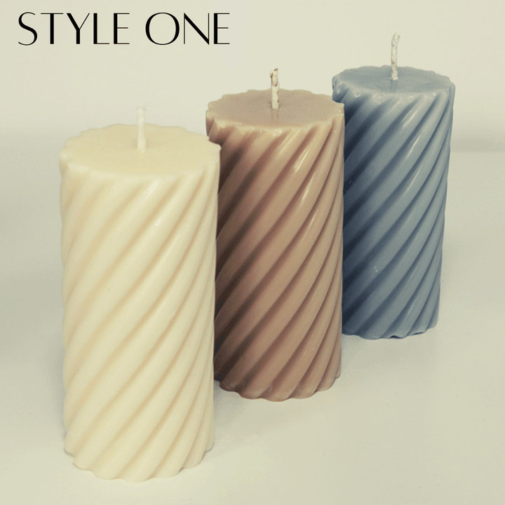 three twisted pillar candles in cream brown and blue on a grey background