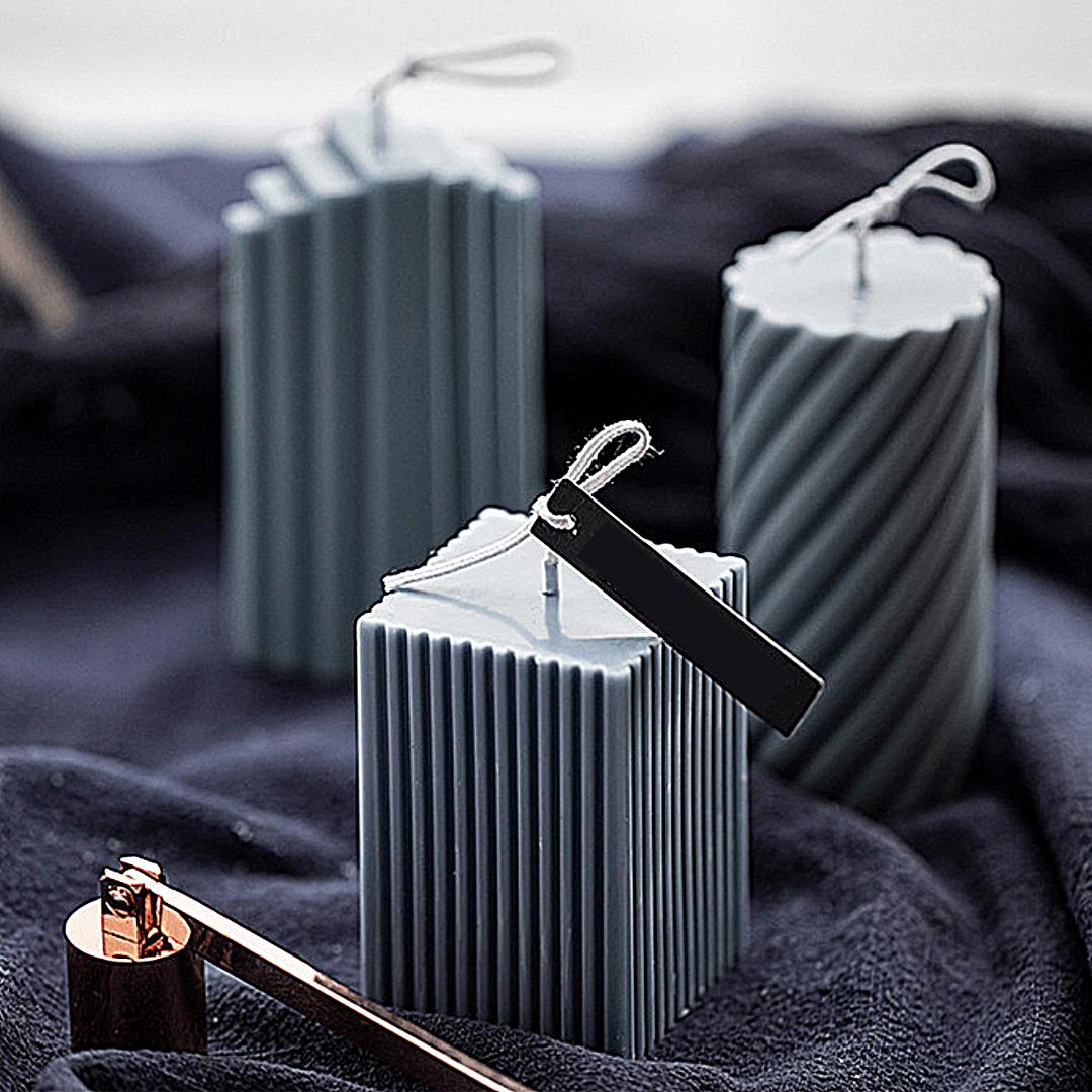 pillar candle mould collection of three different shapes  in grey wax on a textured black background