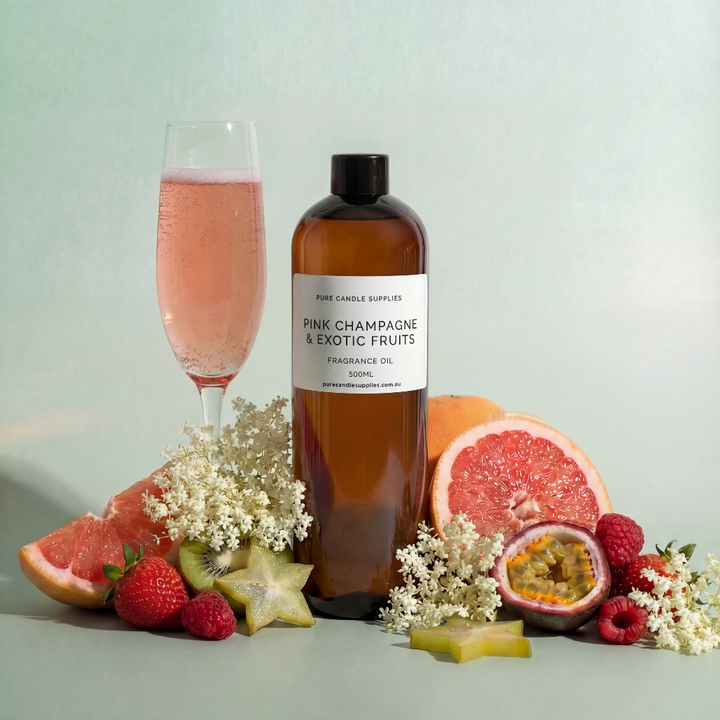 Bottle of 'Pink Champagne & Exotic Fruits' fragrance oil with a glass of pink champagne and fruits on a light background