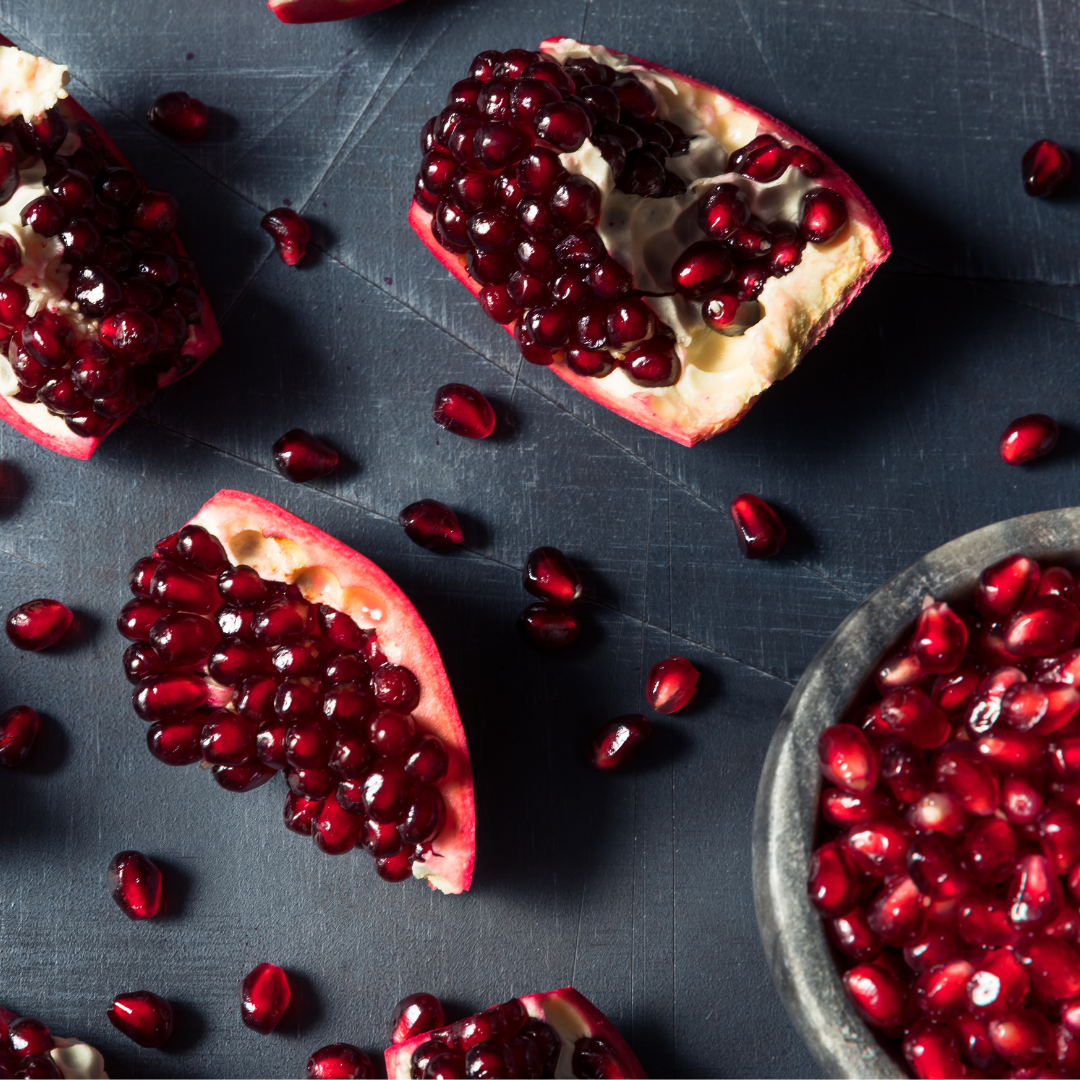 cut pieces of pomegranate fruit with bowl of pomegranate seeds