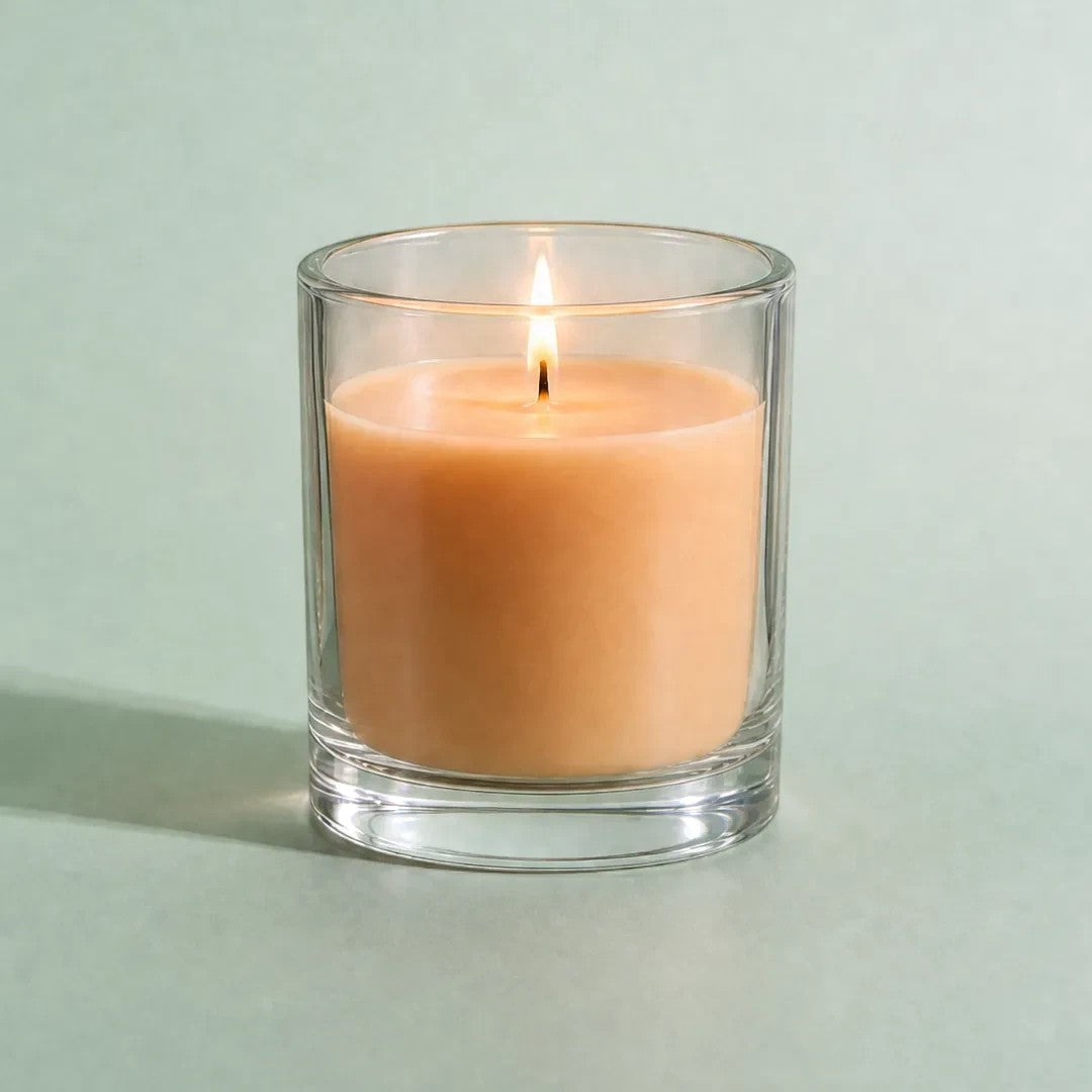 Pure Candle Supplies Melbourne apricot dye chip candle in a clear glass container with a lit wick on a green background