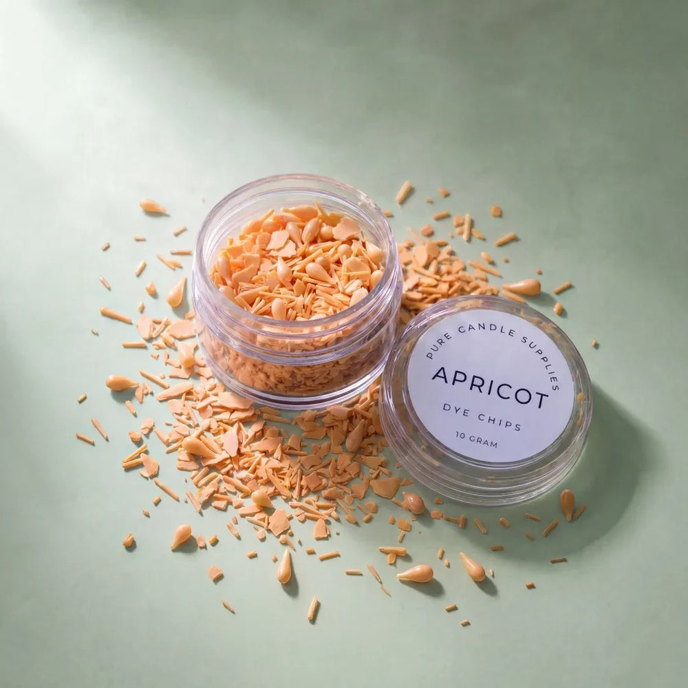Pure Candle Supplies Melbourne apricot dye chips for candle making in a small clear jar on a green surface.