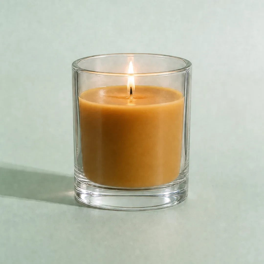 Pure Candle Supplies Melbourne beeswax candle in a clear glass container with a warm glowing flame