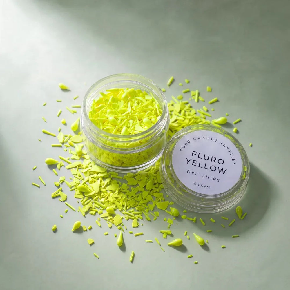 Pure Candle Supplies Melbourne fluro yellow candle dye chips in a small clear jar with loose pieces on a green surface