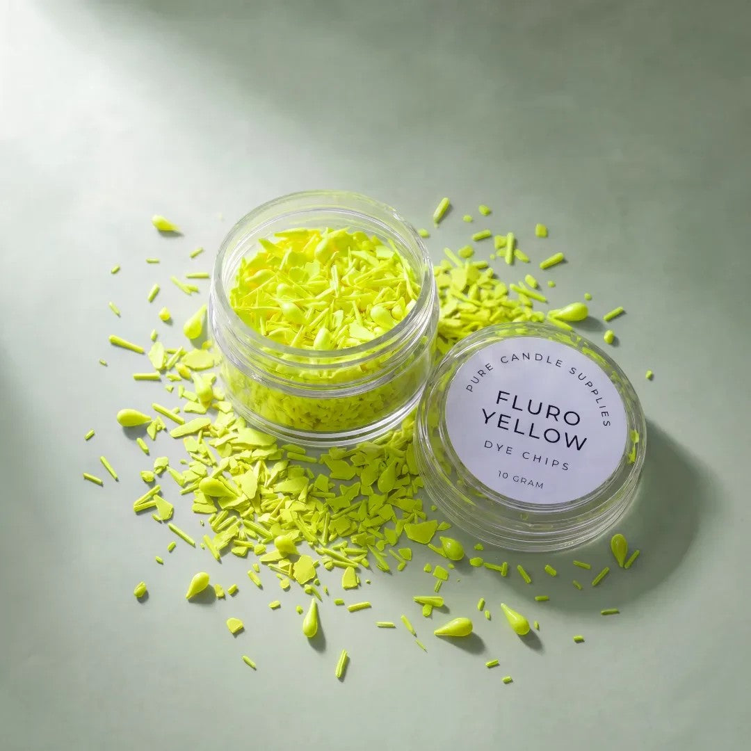 Pure Candle Supplies Melbourne fluro yellow candle dye chips in a small clear jar with loose pieces on a green surface