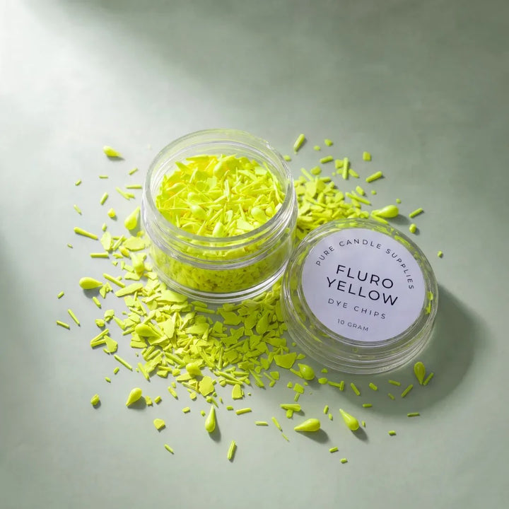 Pure Candle Supplies Melbourne fluro yellow candle dye chips in a small clear jar with loose pieces on a green surface