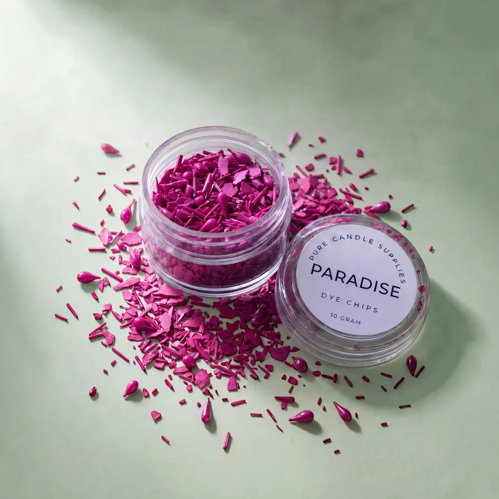 Pure Candle Supplies Melbourne Paradise dye chips in a small jar with vibrant magenta flakes scattered on a green base