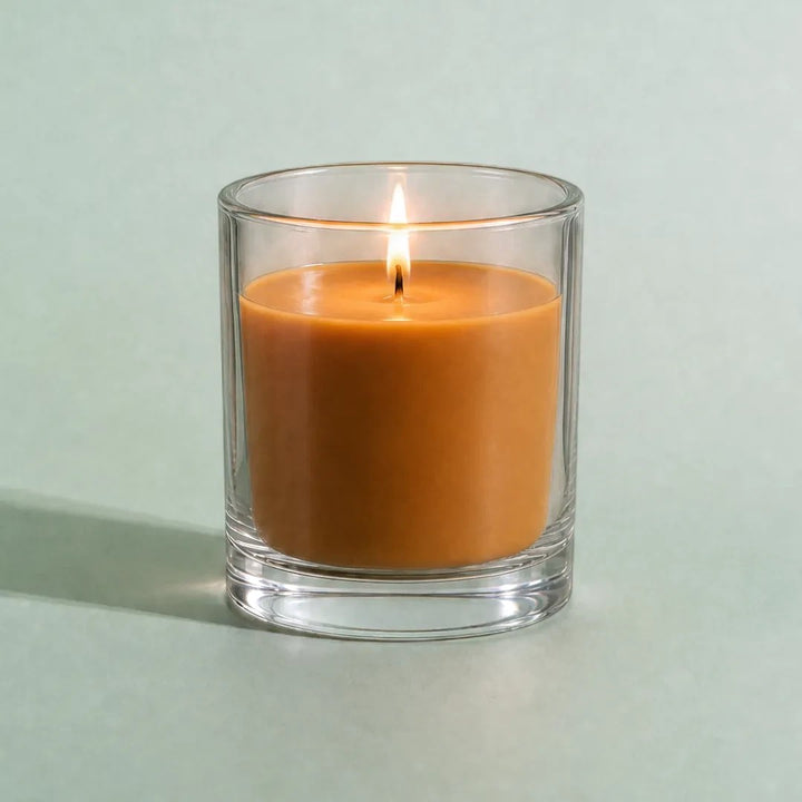 Pure Candle Supplies Melbourne pumpkin spice coloured candle in a clear glass container with a lit wick