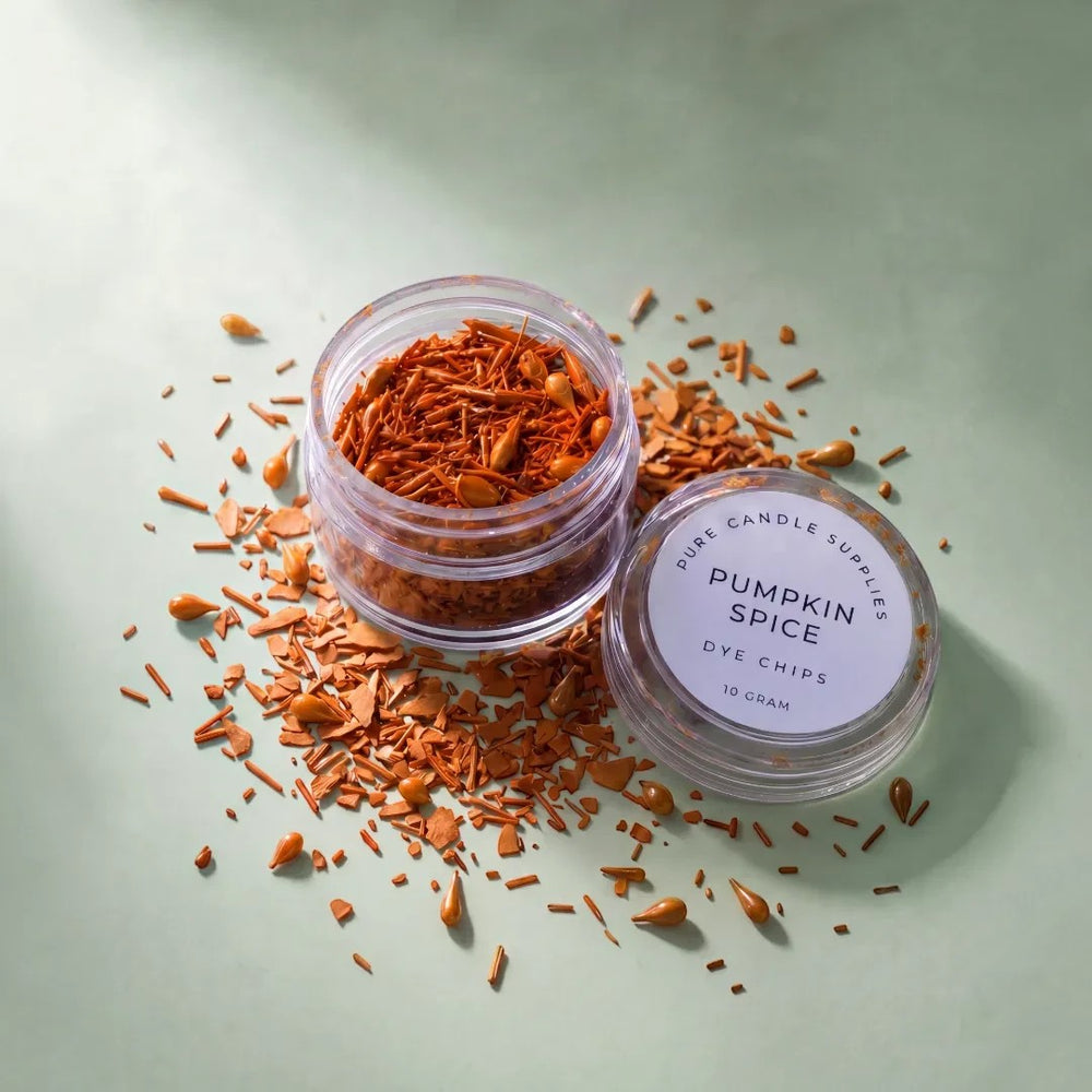 Pure Candle Supplies Melbourne Pumpkin Spice dye chips in a small clear jar with scattered orange wax pieces.