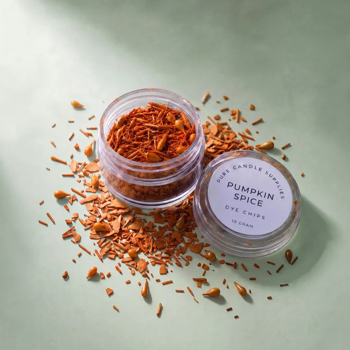 Pure Candle Supplies Melbourne Pumpkin Spice dye chips in a small clear jar with scattered orange wax pieces.
