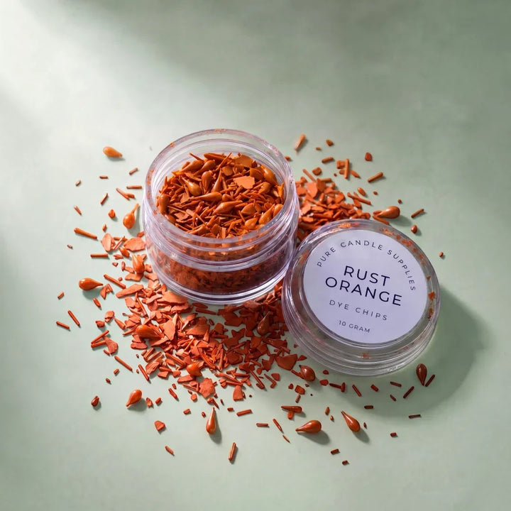 Pure Candle Supplies Melbourne rust orange candle dye chips in a small clear jar on a light green surface.