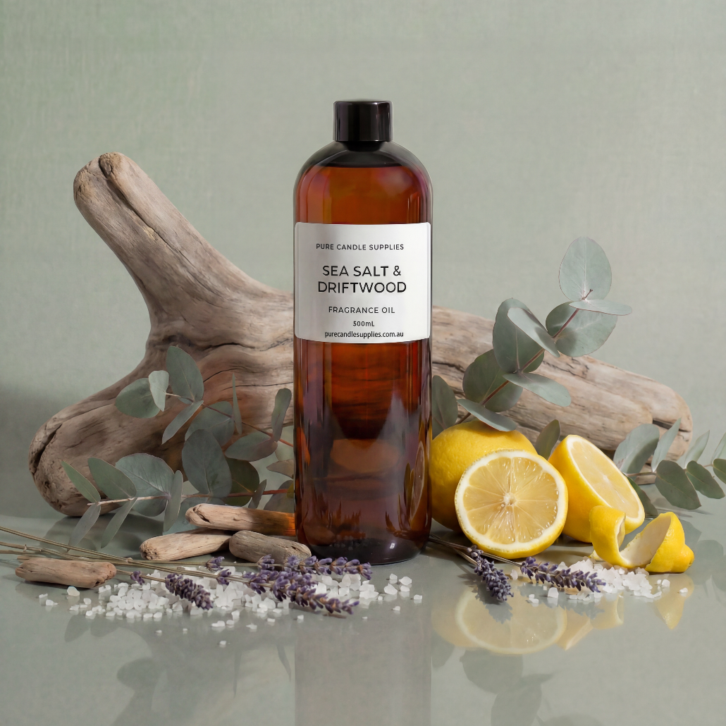 Bottle of 'Sea Salt & Driftwood' fragrance oil with lemons, lavender, and driftwood on a reflective surface.