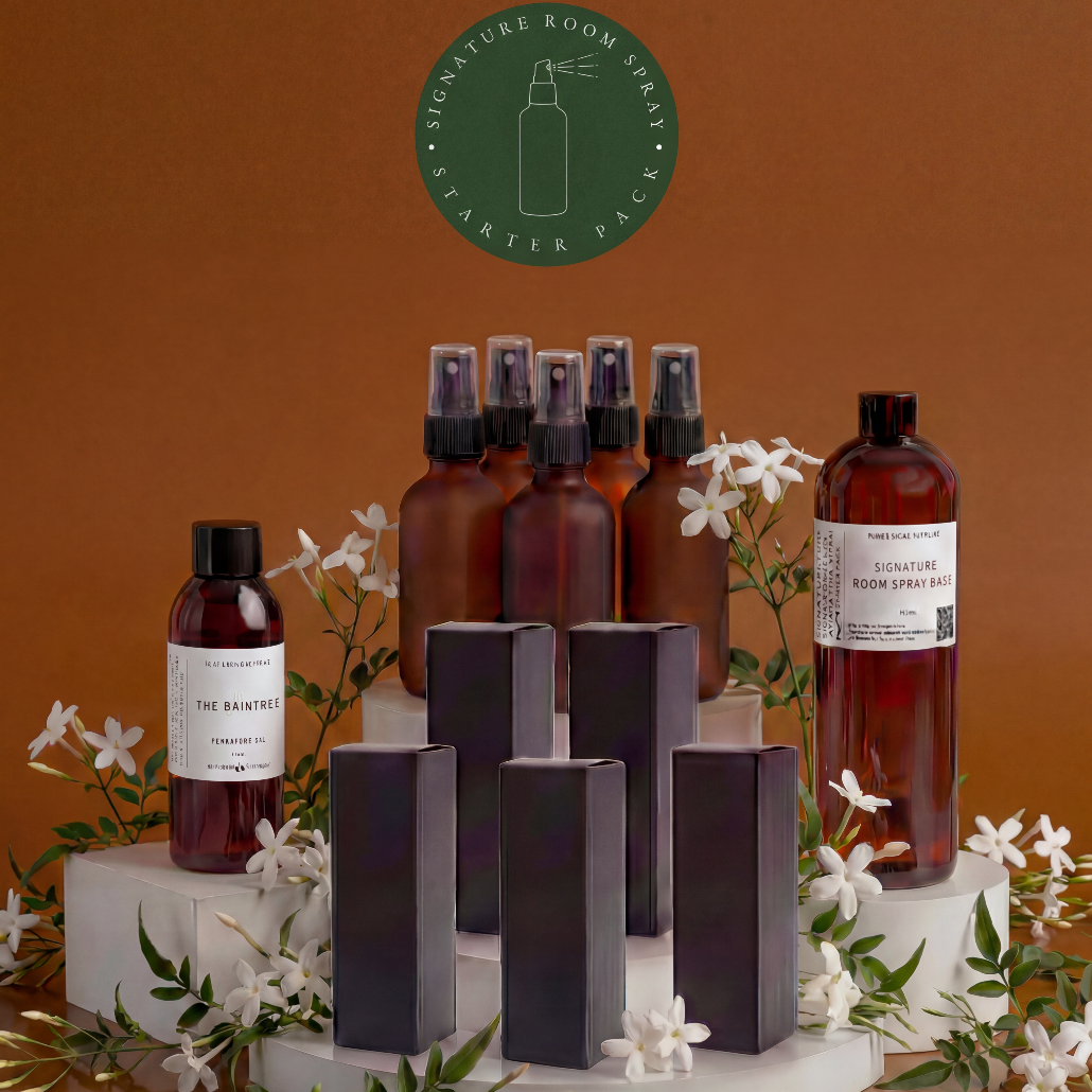 Collection of brown bottles and black packaging on a stand with white flowers and greenery against an orange background.