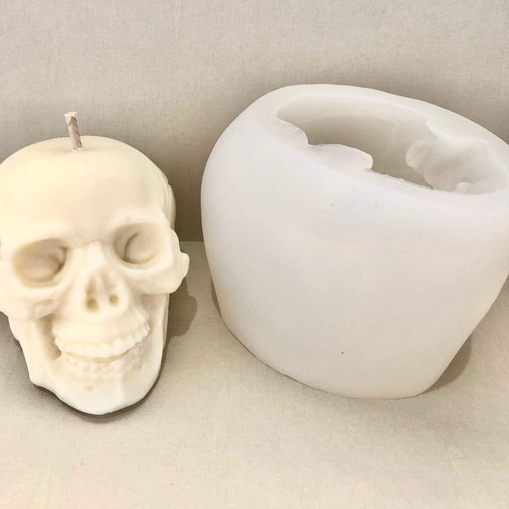 skull shaped candle next to a silicone mould against a beige background