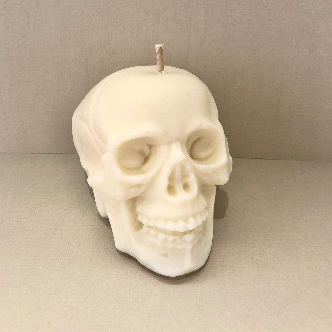 skull shaped candle in white wax against a beige background