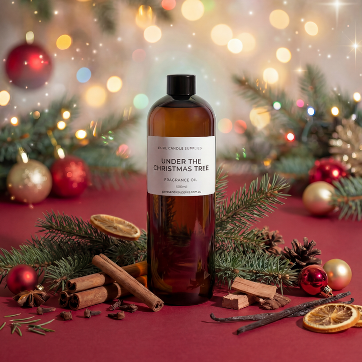Bottle of 'Under the Christmas Tree' fragrance oil with festive decorations on a red background