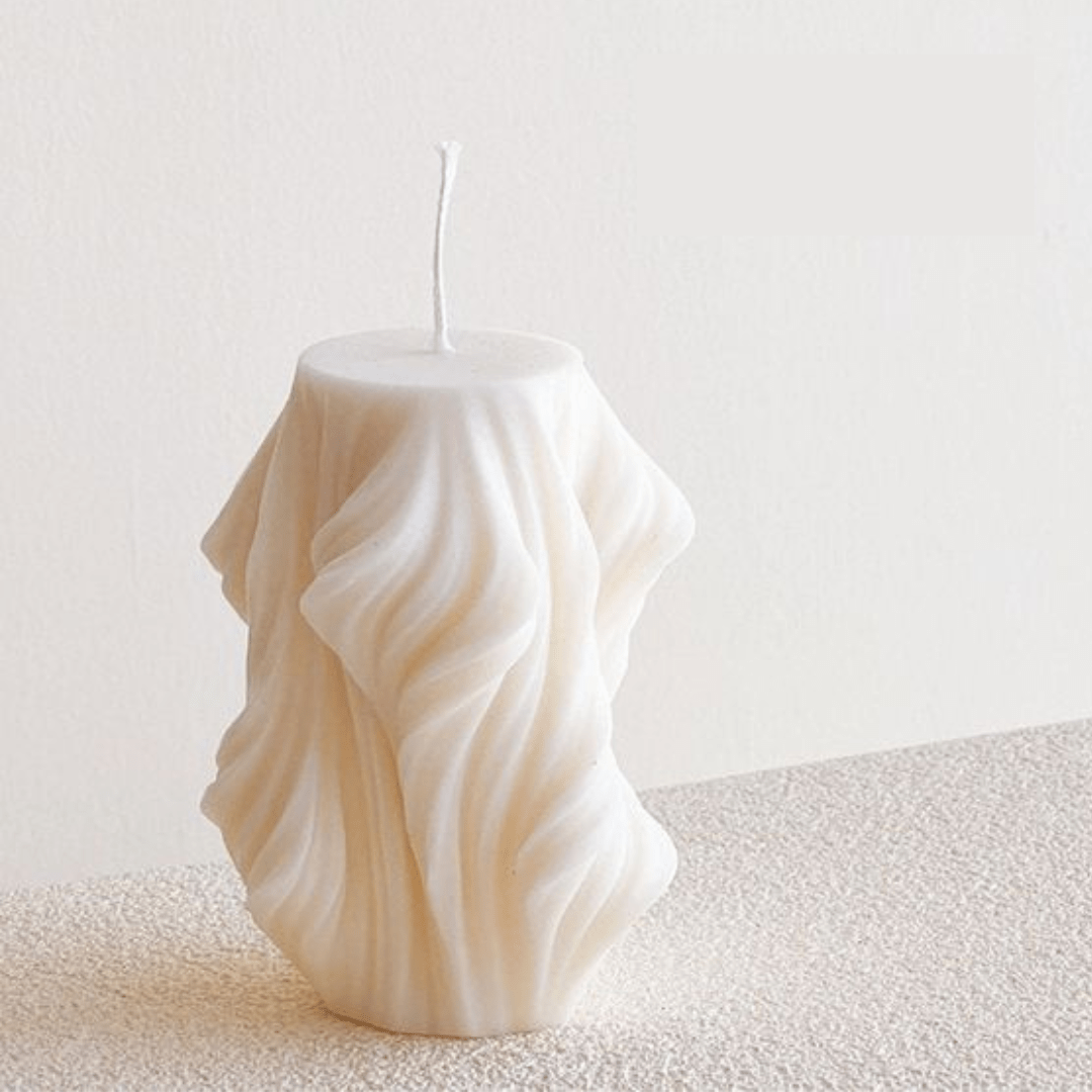 wave shaped pillar candle on textured table against white background